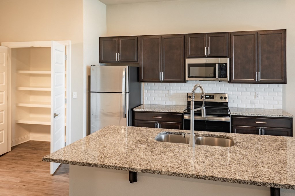 a kitchen with granite countertops and dark wood cabinets