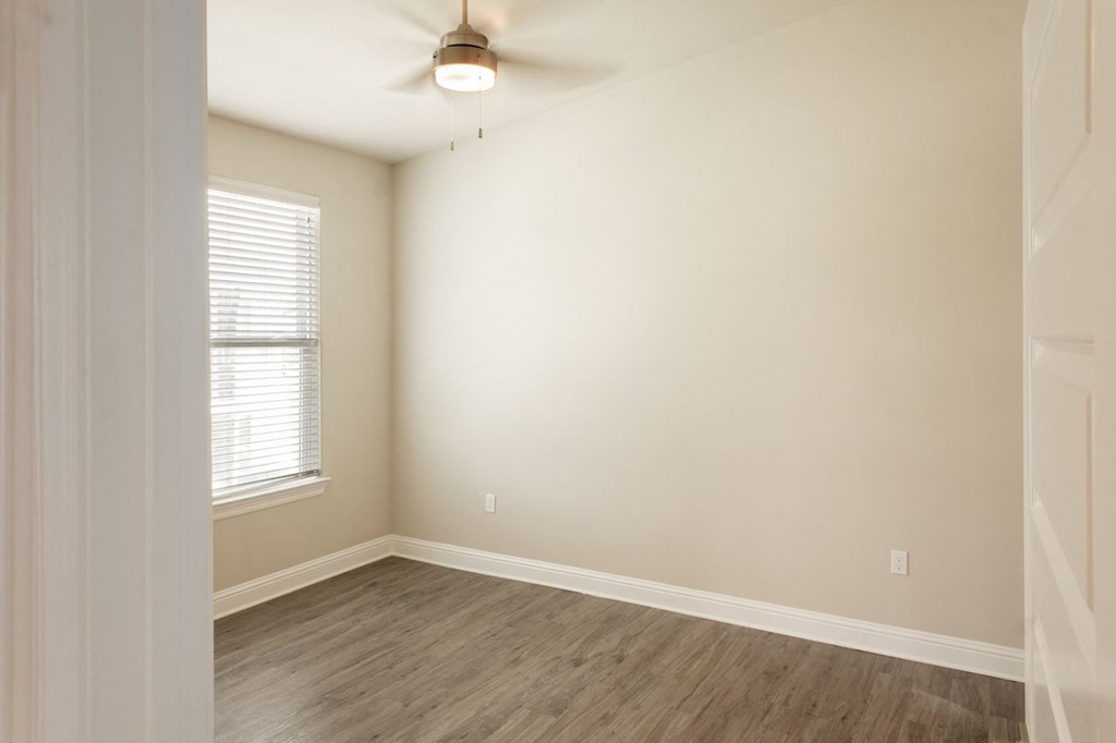 an empty room with a ceiling fan and a window
