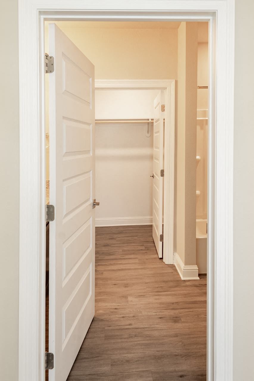 a hallway with a white door and a wooden floor