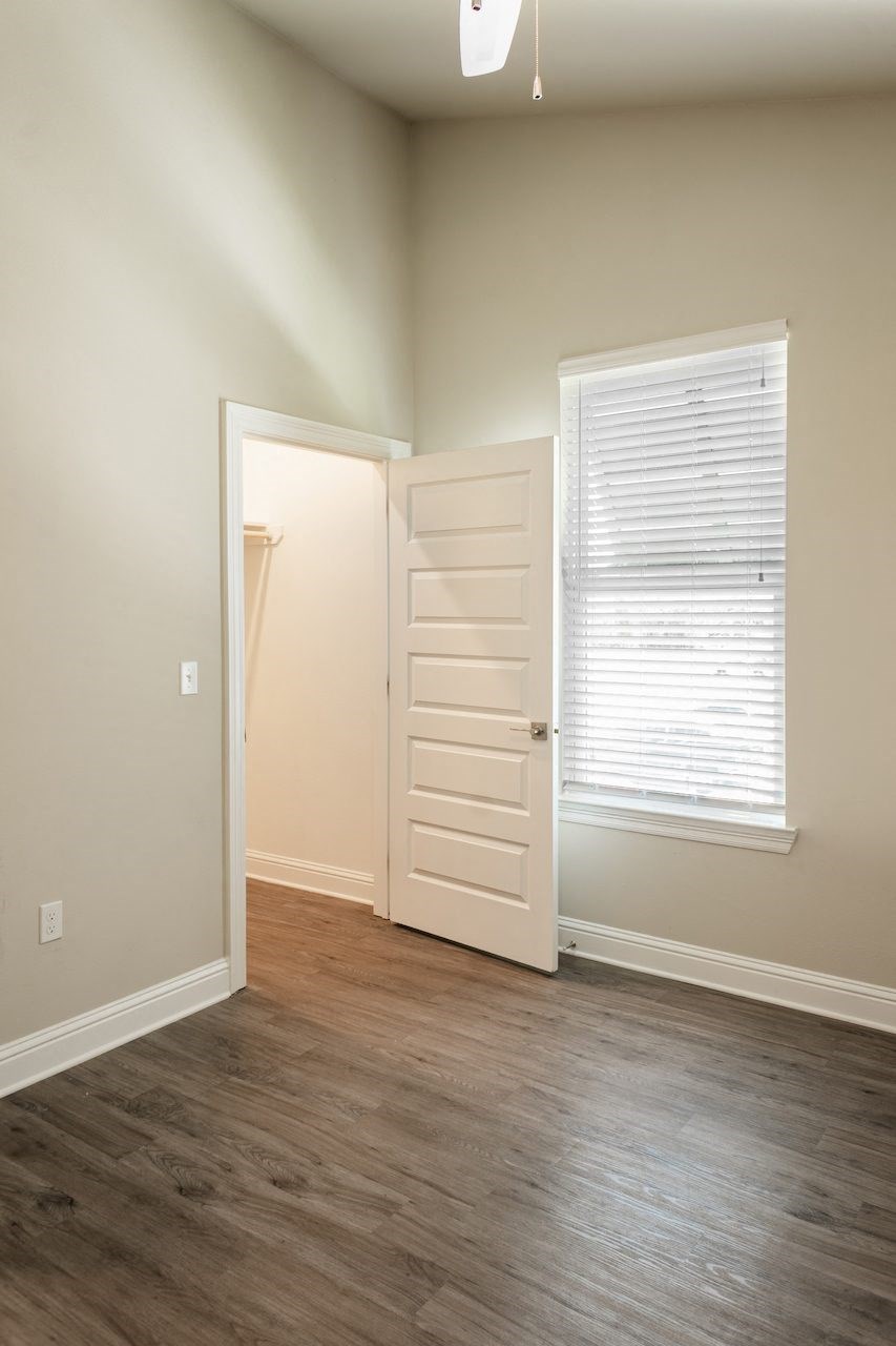 a bedroom with hardwood floors and a large window