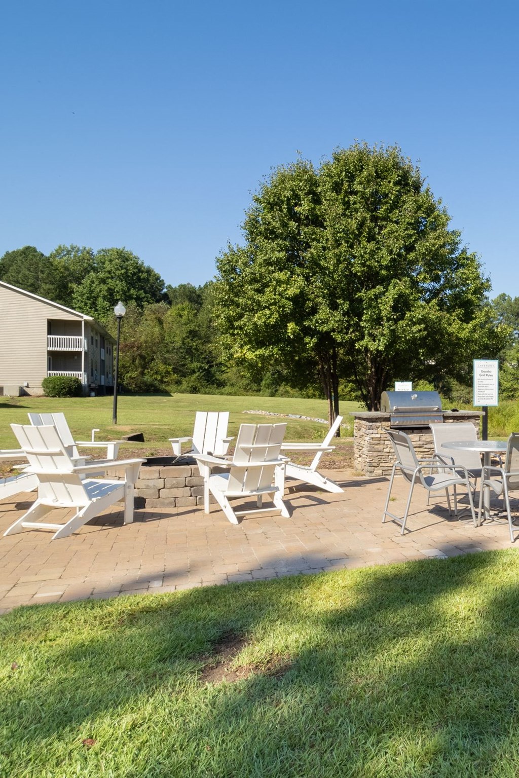 a patio with chairs and tables on a lawn