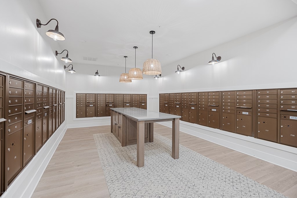 A Spacious Mailroom with an Island Table in the Middle of the Room and locked boxes surrounding.