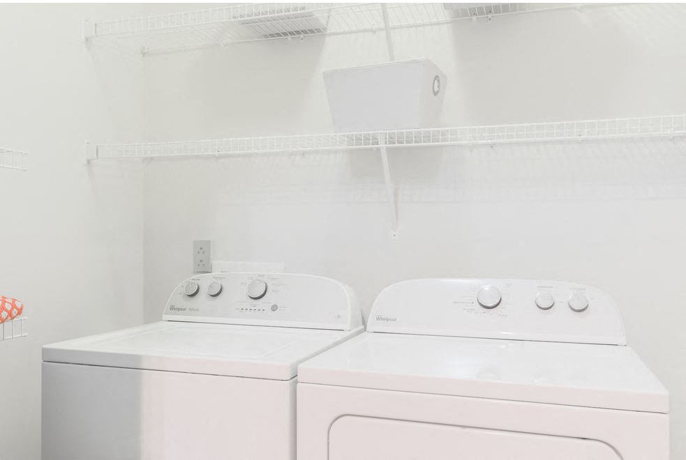 Two white front loading washing machines in a laundry room.