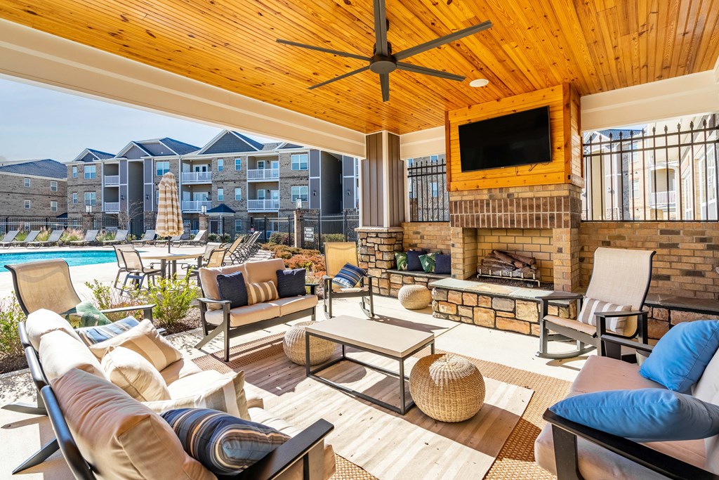 an outdoor living room with a fireplace and a pool