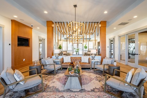 A large, modern living room with a circular rug and a chandelier.