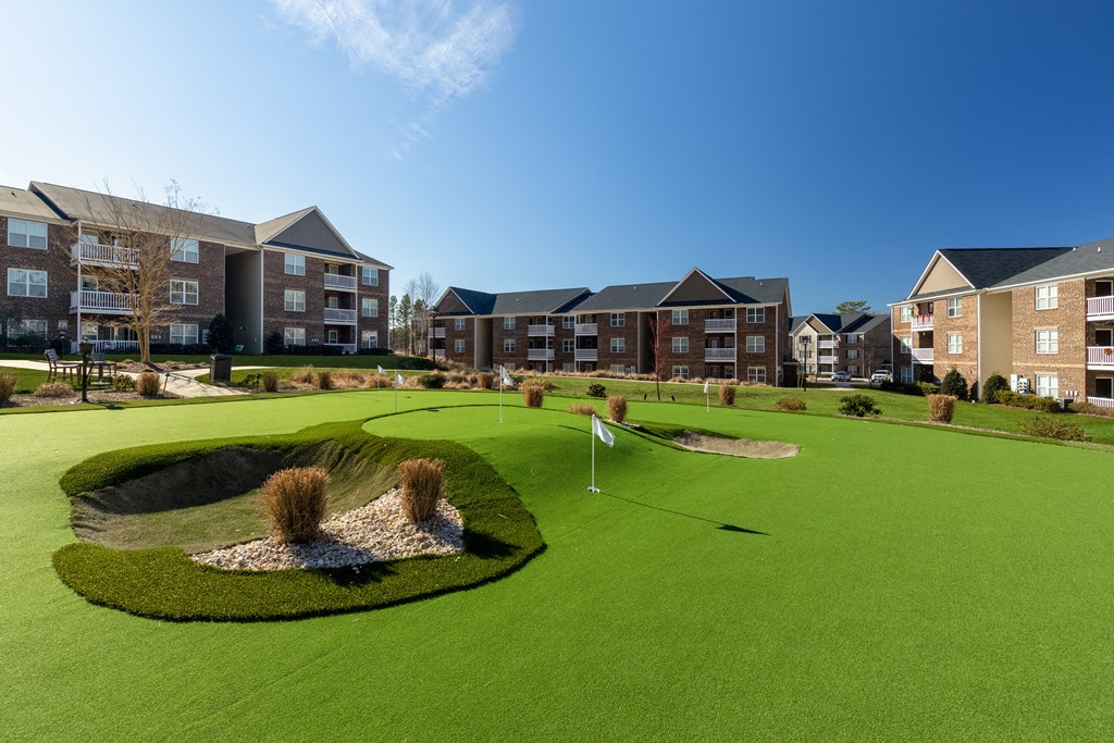 a putting green with an apartment building in the background