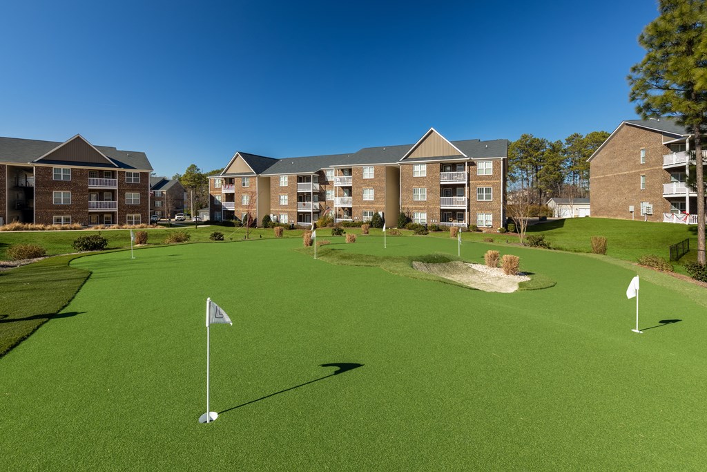 a putting green with apartments in the background