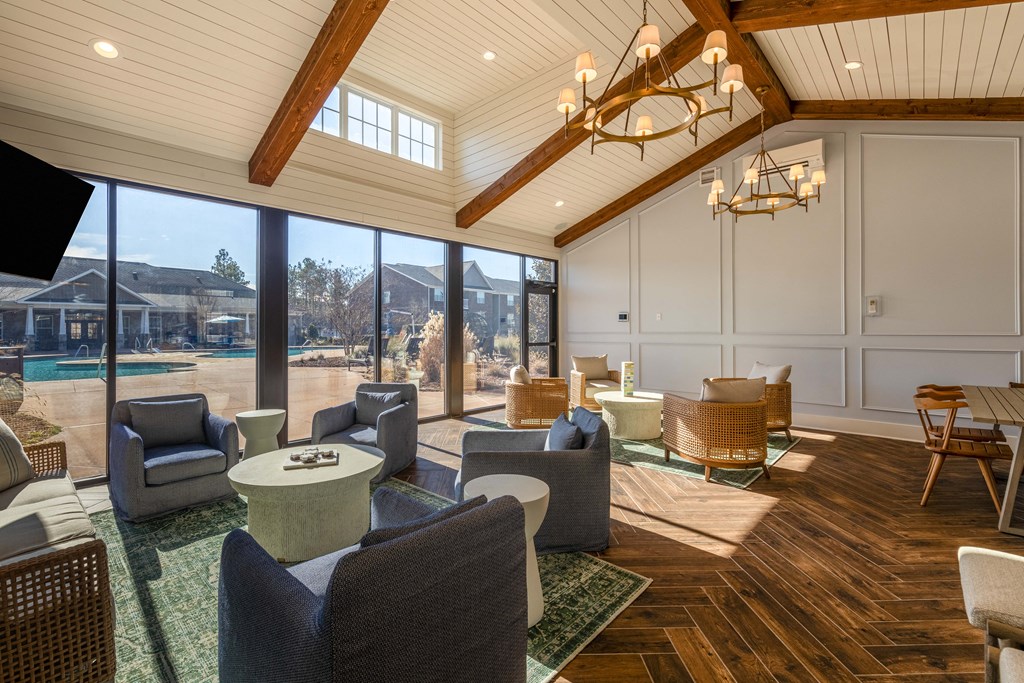 a large living room with chairs and tables and a view of a pool