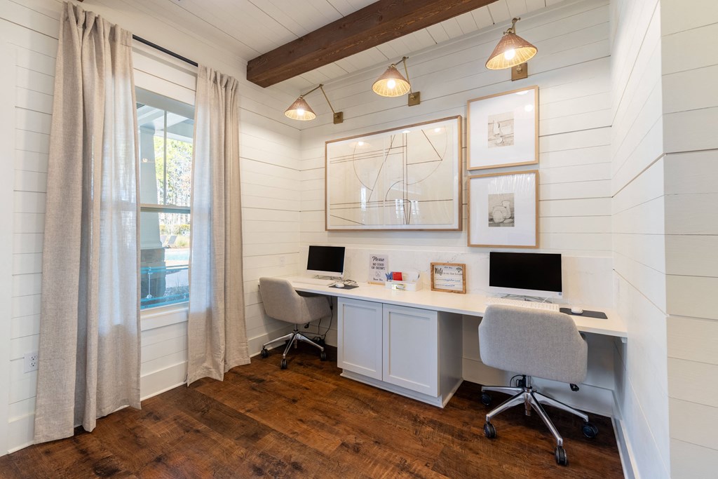 a home office with white shiplap walls and a desk with two computers