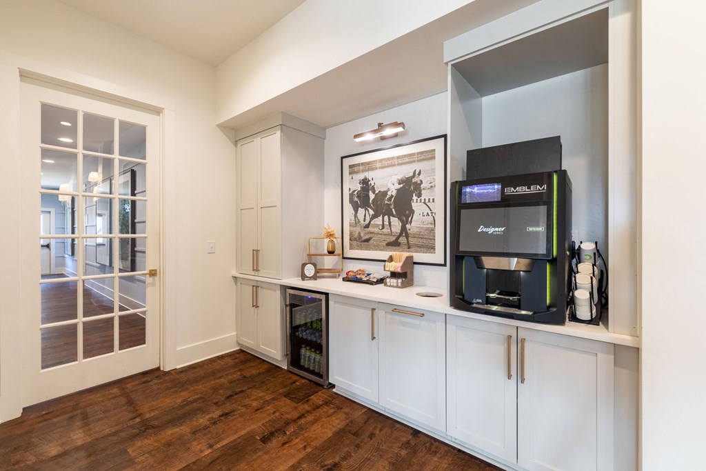 a kitchen with white cabinets and a coffee machine and a television