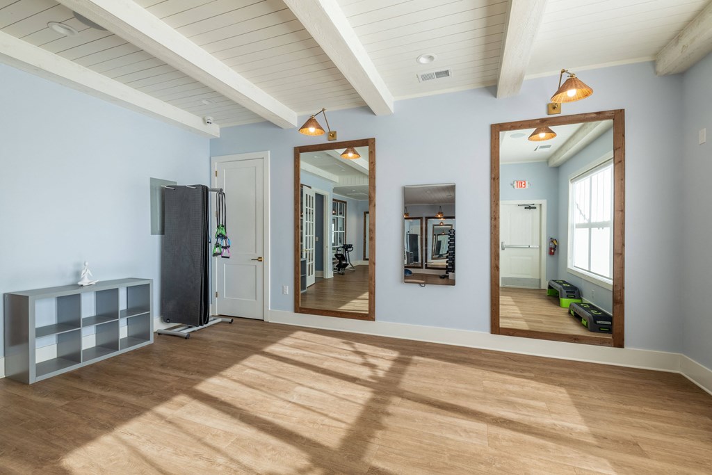 a living room with three mirrors and a wood floor