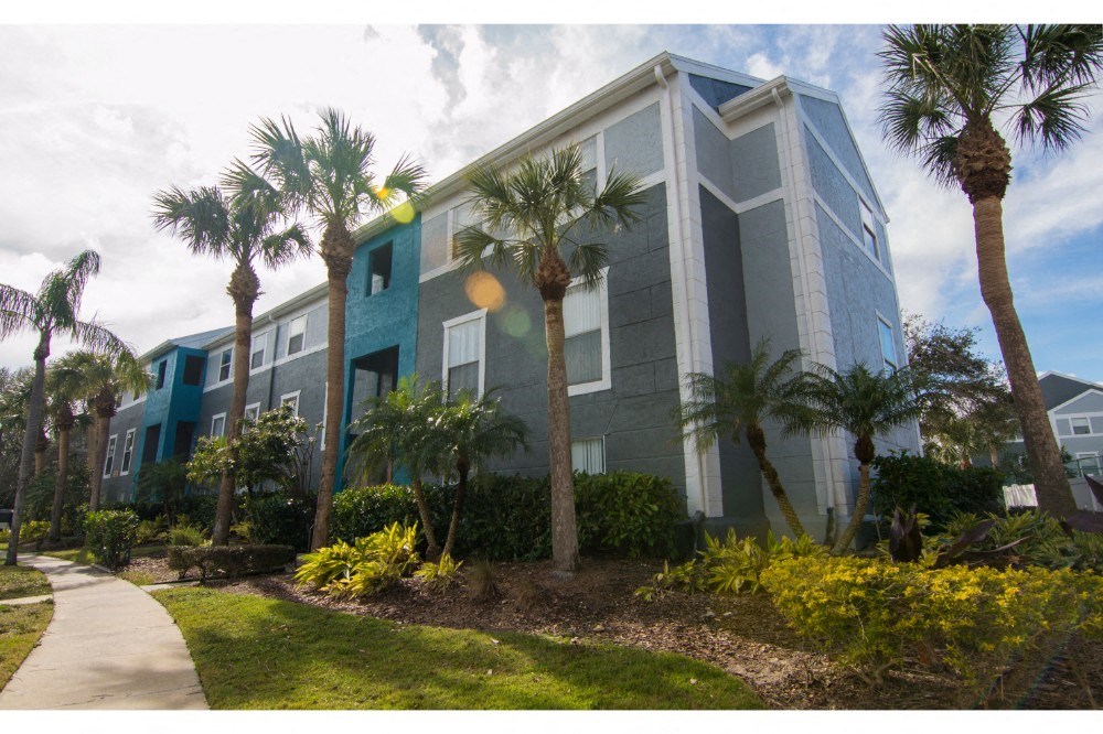 a building with palm trees in front of it and a sidewalk