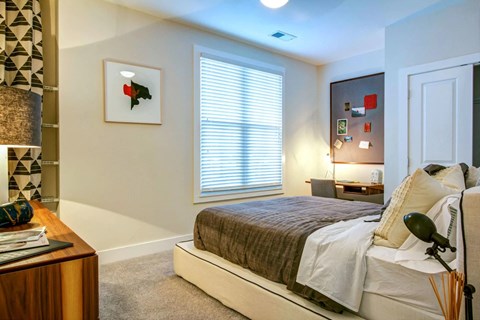 A bedroom with a bed, nightstand, and a picture on the wall.