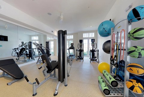 A gym with a variety of equipment including weights and exercise balls.