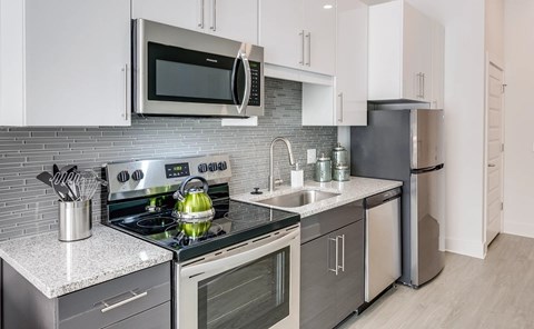 A modern kitchen with a stove top oven, microwave, and refrigerator.