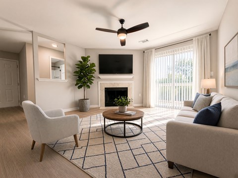 A living room with a fireplace, a chair, a couch, a coffee table, and a plant.