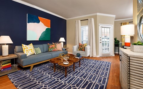 A living room with a blue couch and a painting on the wall.