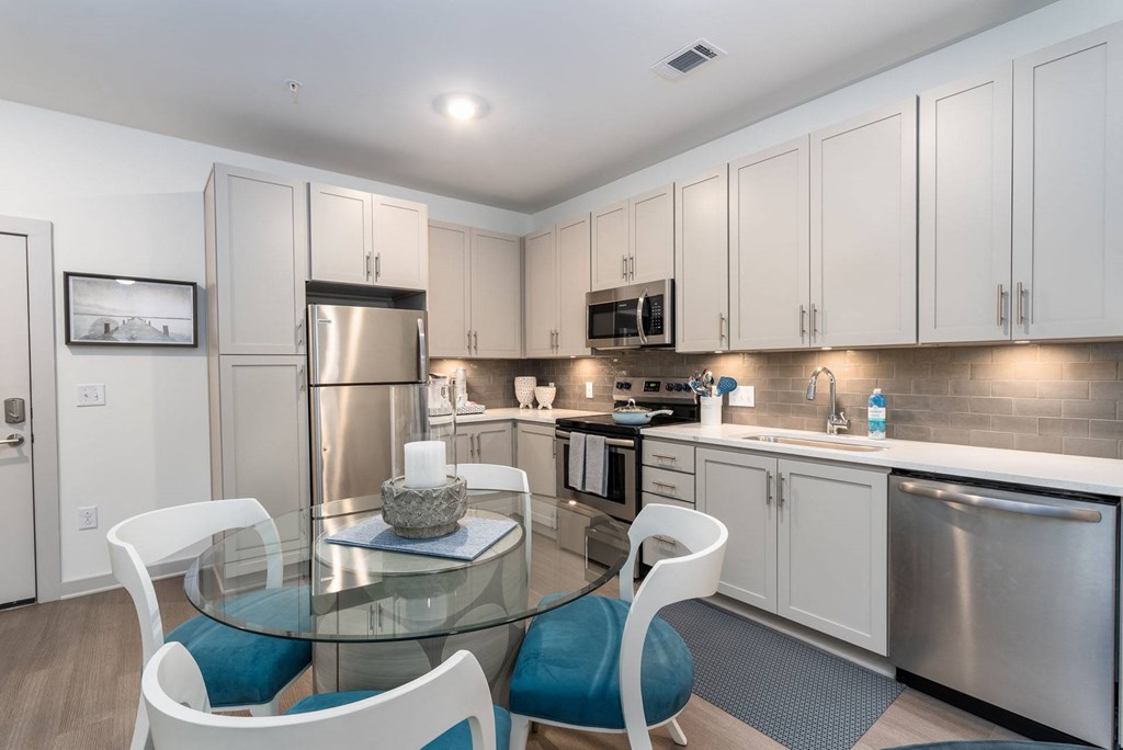 a kitchen and dining room with white cabinets and stainless steel appliances