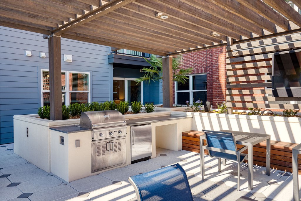 a patio with a barbecue grill and a table and chairs