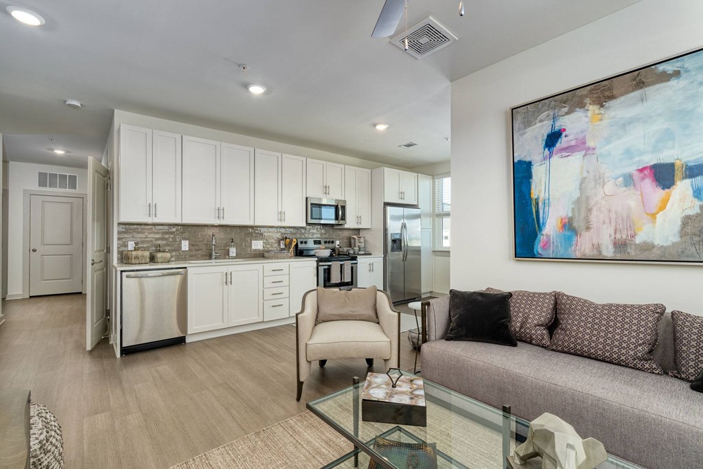 a living room and kitchen with a couch and a glass table