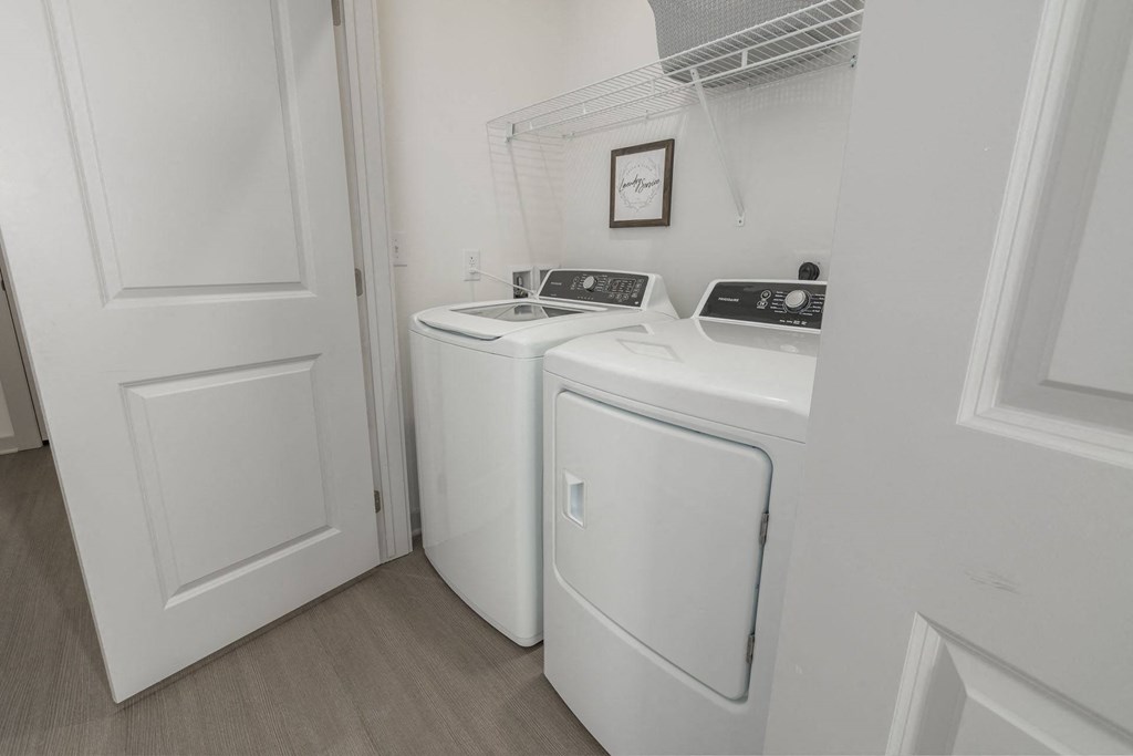 a washer and dryer in a laundry room with white cabinets and a door