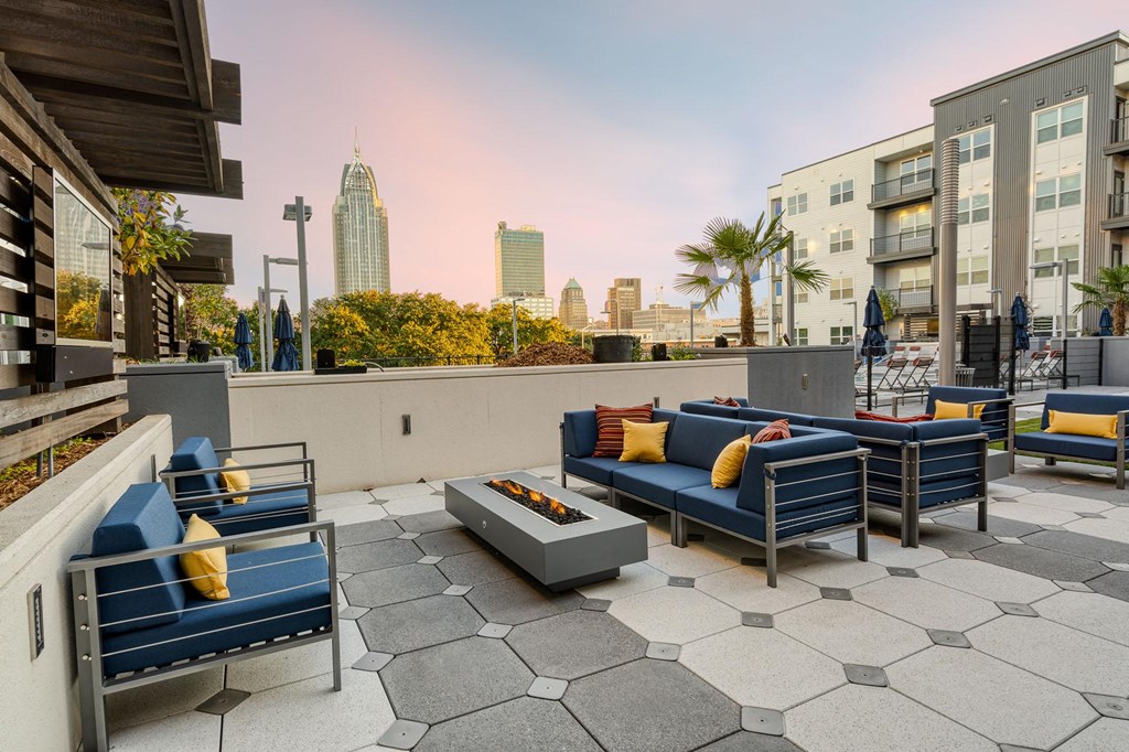 a rooftop patio with blue couches and chairs and a fire pit