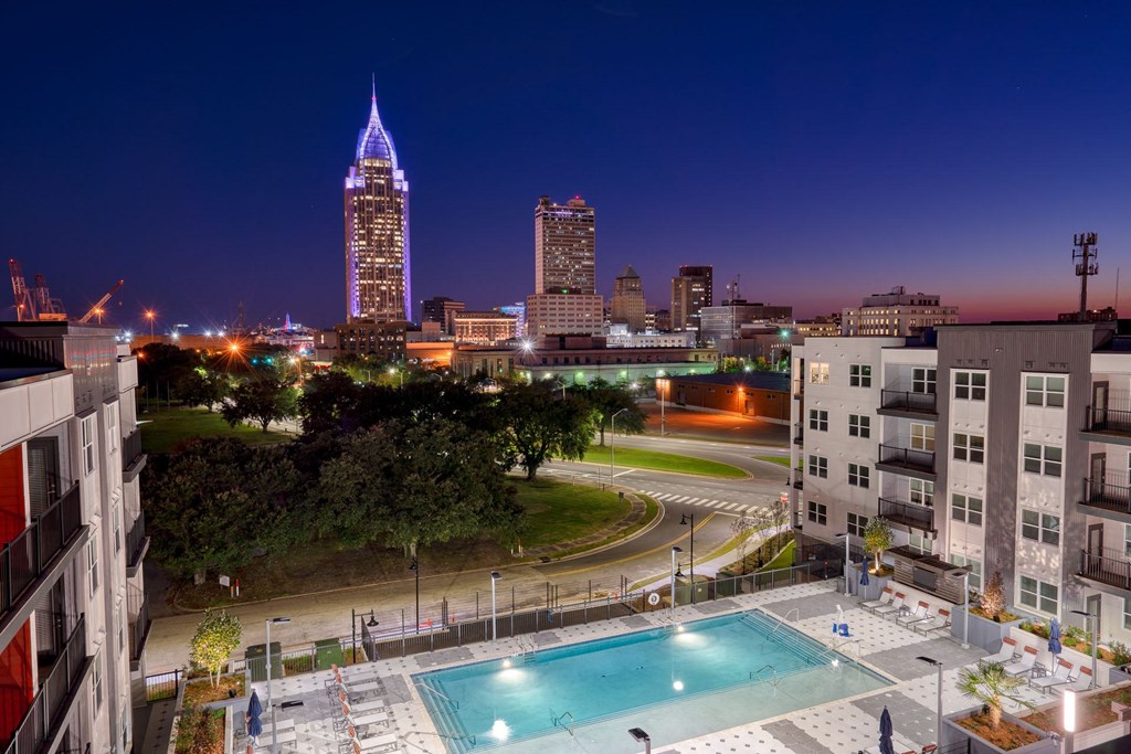 a city at night with a pool and a view of the city