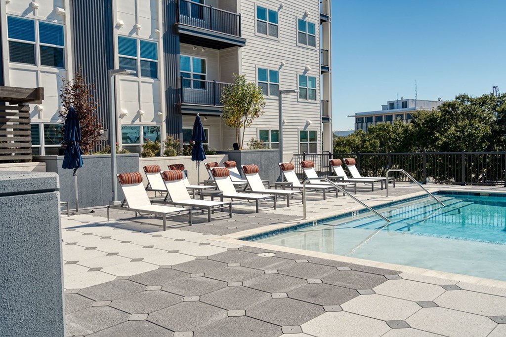 a swimming pool with lounge chairs next to a building