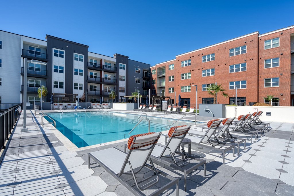 a pool with chairs and a building in the background