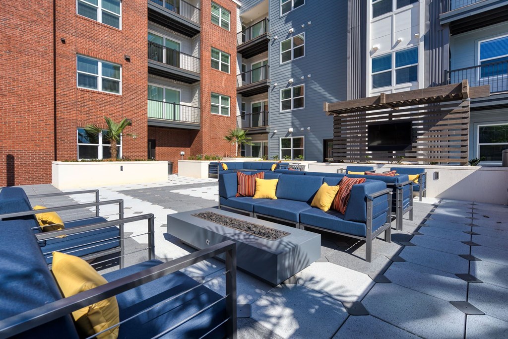 a large patio with blue couches and a fire pit