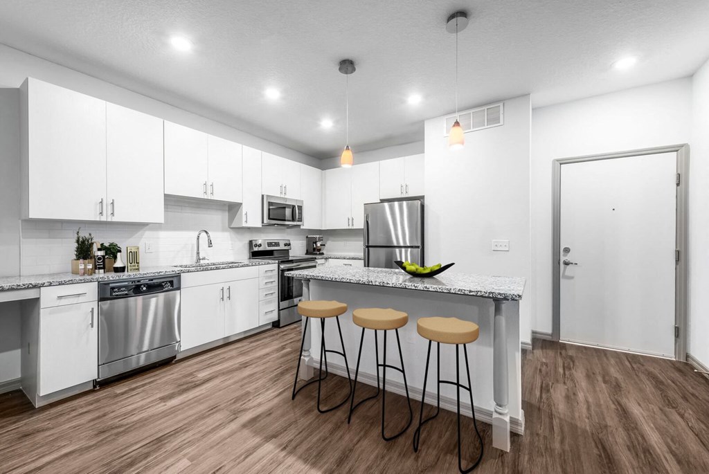 a kitchen with white cabinets and a counter top with three stools