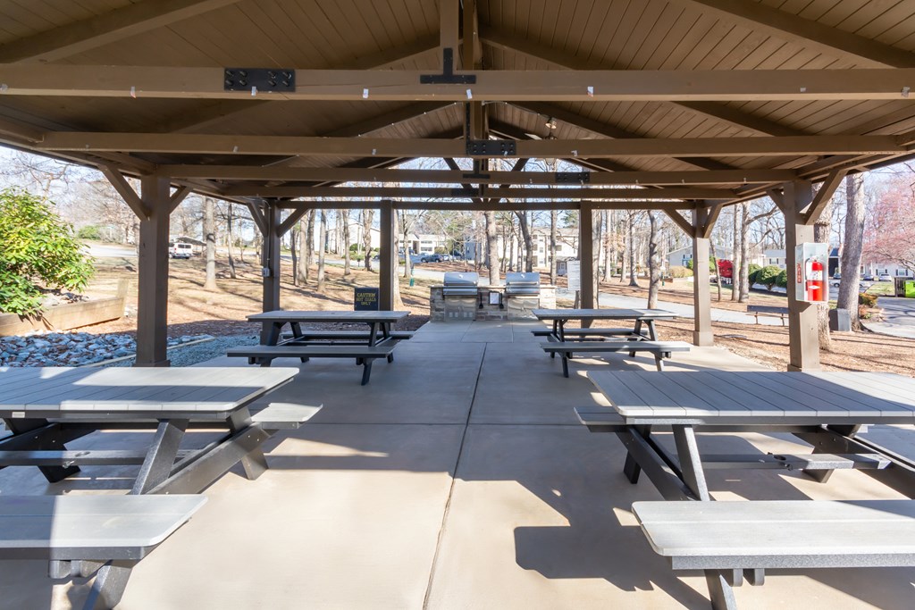 A covered picnic area with tables and benches at Madison Woods apartments in Greensboro, NC.