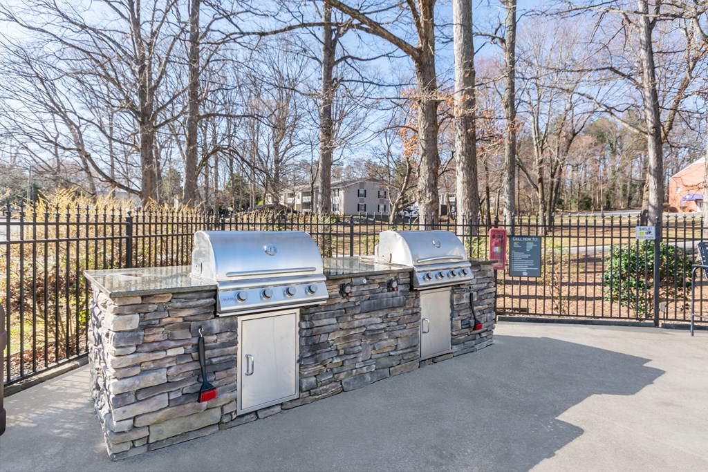 A stone wall with two built-in grills on top. at Madison Woods apartments in Greensboro, NC