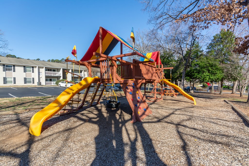 A playground with a yellow slide and a red and yellow structure at Madison Woods apartments in Greensboro, NC.