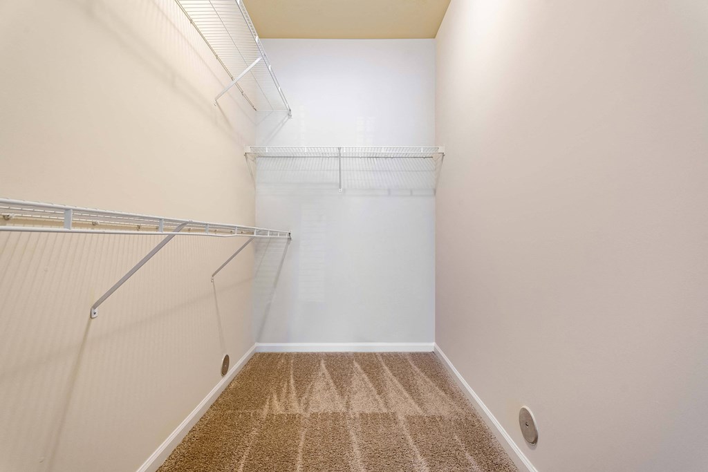 a spacious walk in closet with a mirrored wall and a hanging rack