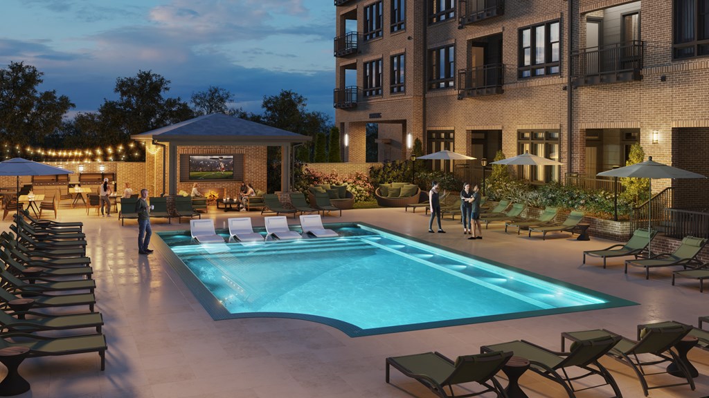 A pool area with lounge chairs and umbrellas is lit up at dusk.