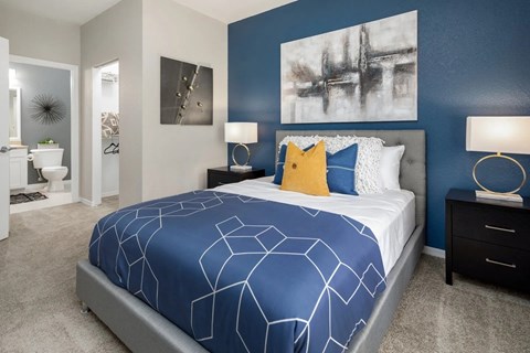 A bedroom with a large bed, pillows and a painting on the wall.