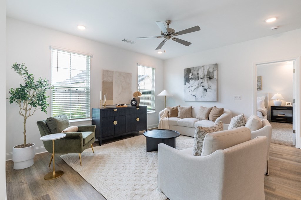 a living room with couches and chairs and a ceiling fan