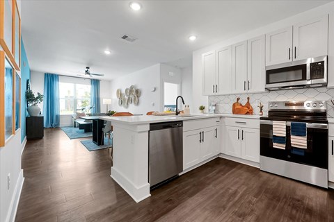 A modern kitchen with white cabinets and stainless steel appliances.