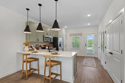 A kitchen with a white counter and wooden bar stools.