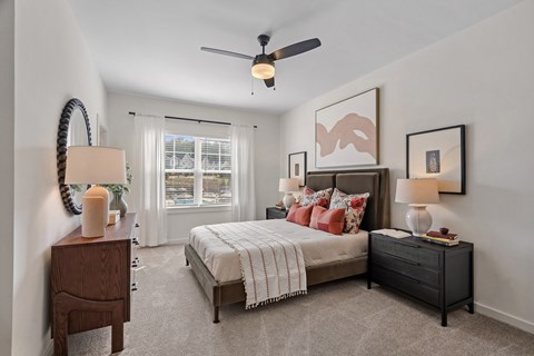 A bedroom with a bed, nightstand, and a ceiling fan.