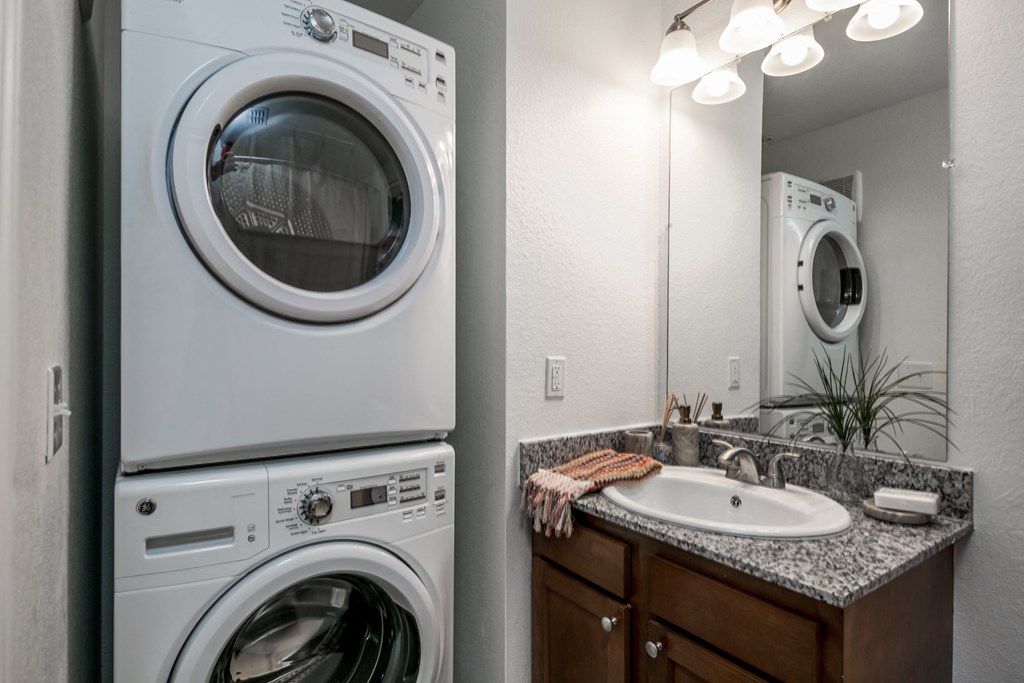 a washer and dryer in a bathroom with a sink and a mirror