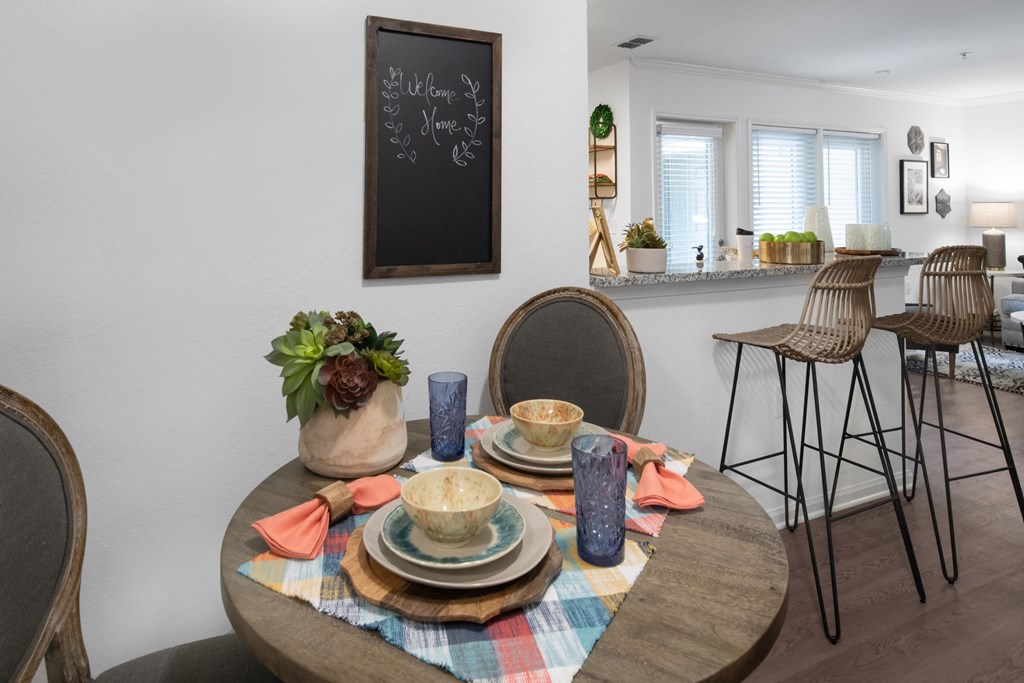 a dining room with a table and chairs and a kitchen with a bar and a