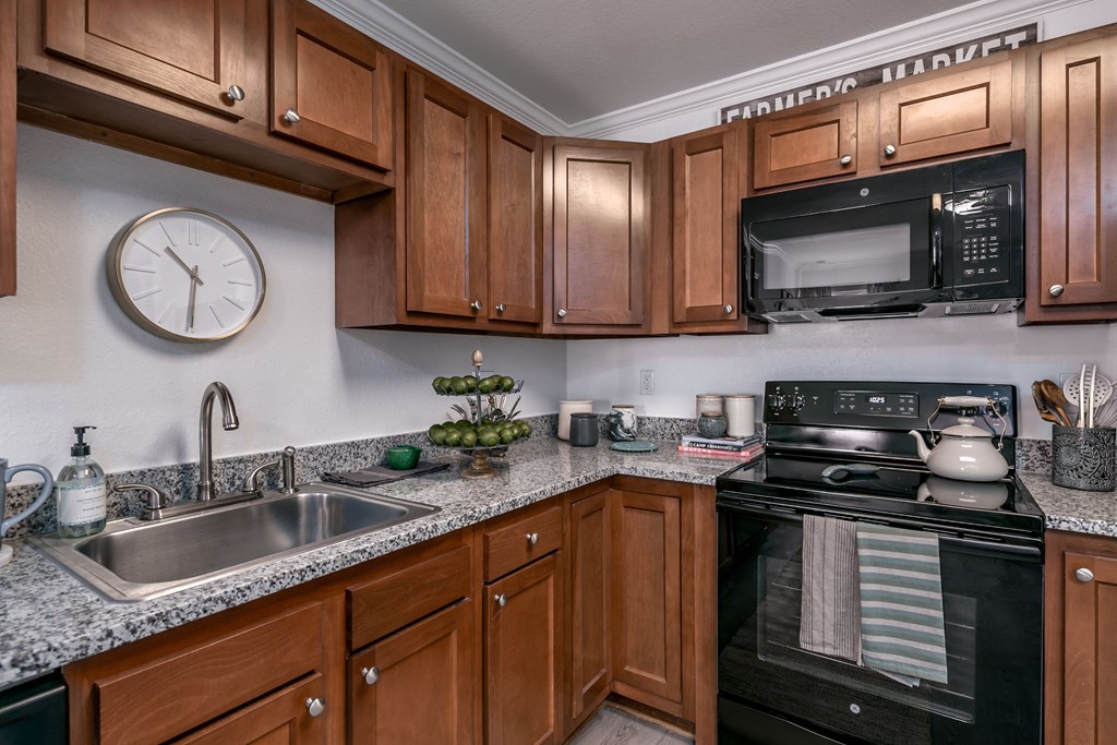 full kitchen with black appliances and granite counter tops and a clock