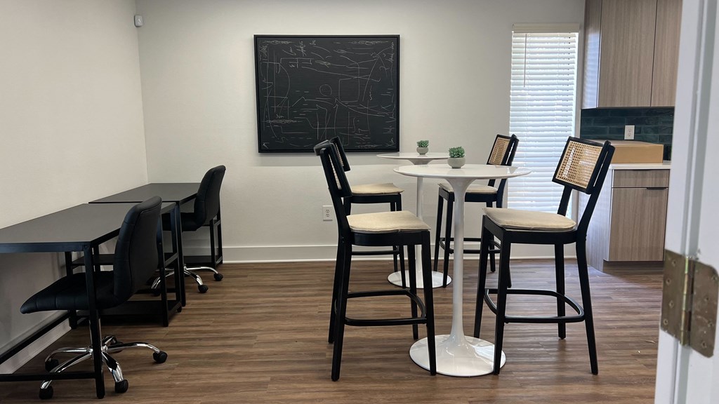 an office with tables and chairs and a chalkboard on the wall