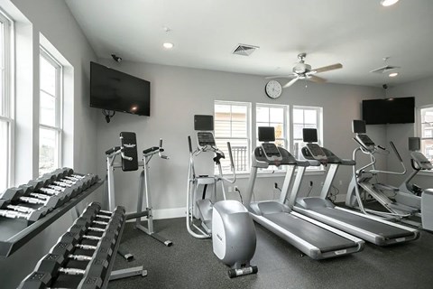 Spacious gym with treadmills, elliptical machines and a television.
