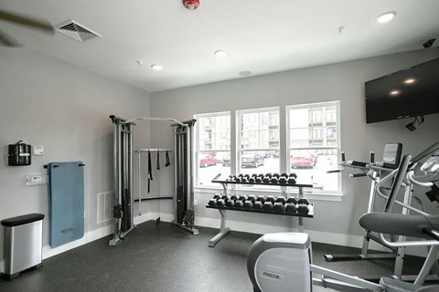 A gym with a variety of equipment including a weight bench, a squat rack and a rowing machine.