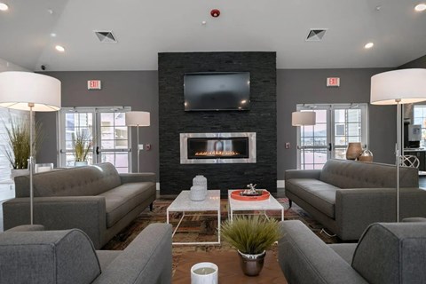 Clubhouse living room with a fireplace and grey couches.