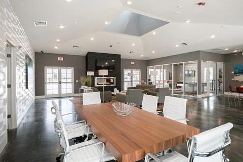 A modern dining room with a wooden table and white chairs in the clubhouse.