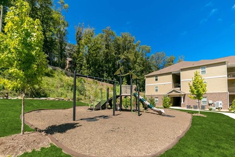A playground with a green slide and a brown sandbox.
